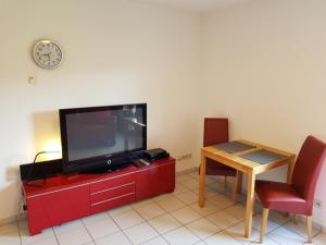 a living room with a tv on a red cabinet with a table at Ferienwohnung Sonnenfels **** in Bad Ems
