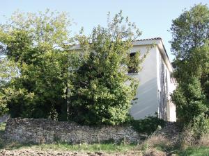 a house with a stone wall and trees at Gîte La Capitelle in Boissières