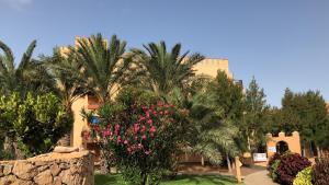 a building with palm trees and pink flowers in a yard at Wellenkind Surfschool in La Pared