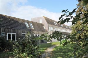 a row of wooden buildings with a yard at Appartement De Parel, Resort Amelander Kaap in Hollum