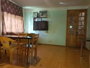 a dining room with a table and chairs and a television at Hostel SvanLand in Mestia
