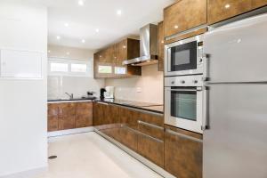 a kitchen with wooden cabinets and a white refrigerator at Victory Village 2A in Quinta do Lago