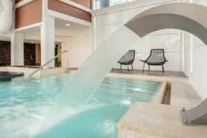 a water fountain in a swimming pool with two chairs at Hotel Baia Flaminia in Pesaro