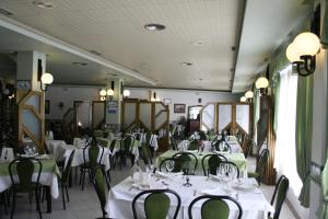 a dining room with white tables and green chairs at El Paso in Águilas