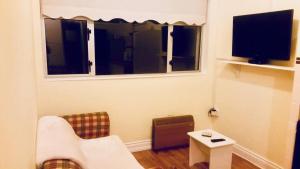 una pequeña sala de estar con TV y sofá en Enniscrone Apartment, en Enniscrone