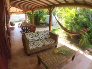 - une terrasse couverte avec un hamac, une chaise et une table dans l'établissement Villa des Amandiers, à Les Anses-d'Arlet
