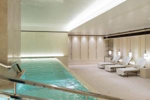 a pool in a hotel room with chairs and a swimming pool at The Lanesborough, Oetker Hotels in London