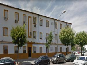 un gran edificio blanco con coches aparcados en un aparcamiento en DS Apartamento Mezquita con cochera, en Córdoba