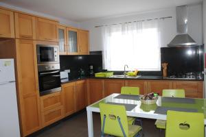 a kitchen with wooden cabinets and a table with chairs at Hills and Atlantic Ocean retreat - Conceição House in Calheta