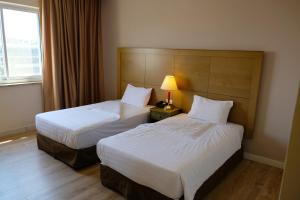 una habitación de hotel con 2 camas y una lámpara en Ritz Hotel, en Jerusalén