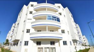 a white apartment building with a blue sky in the background at Agadir Beach Appartment in Agadir