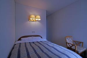 1 dormitorio con cama, silla y luces en Pension Entre - deux - Mers, en Hachimantai