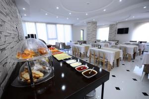 a restaurant with tables and chairs with food on a buffet at Dream Tower in Batumi