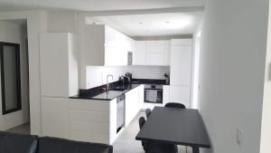a kitchen with white cabinets and a black table at Anatole - T3 - Moderne - Climatisé - 1er étage - Très grande terrasse - Vue magnifique et dégagée in Saint-Mandrier-sur-Mer