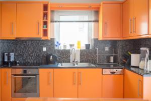 an orange kitchen with a sink and a window at Designer's apartment close to city center in Athens