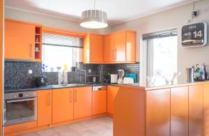 an orange kitchen with orange cabinets and a window at Designer's apartment close to city center in Athens