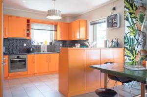 a kitchen with orange cabinets and a table at Designer's apartment close to city center in Athens