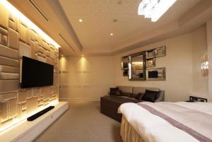 名古屋市にあるN ホテルのベッドルーム(ベッド1台、テレビ、ソファ付)