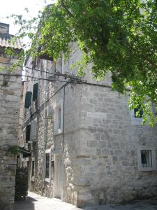 kamienny budynek z białymi drzwiami i drzewem w obiekcie Split Central Guesthouse w Splicie