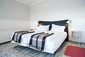 a bedroom with a white bed with a black headboard at Kleifar: Ocean View Apartment in Hellissandur