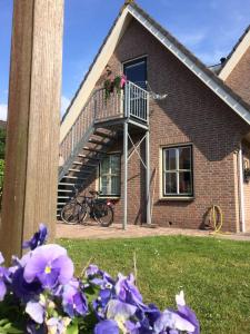 una casa con una escalera y flores púrpuras en el patio en De Slotruine, en Egmond aan den Hoef