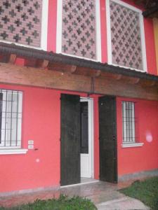 a red house with two doors in front of it at casa in campagna _LORI in Volta Mantovana