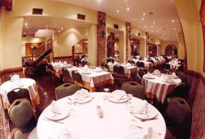 una sala da pranzo con tavoli e sedie bianchi di ArielMardel a Mar del Plata