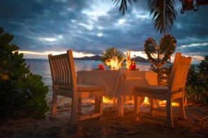 a table and chairs on the beach at night at La Digue Island Lodge in La Digue