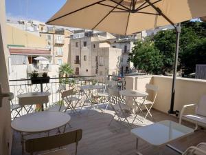 a patio with tables and chairs and an umbrella at Marina Blu Rooms in Castellammare del Golfo