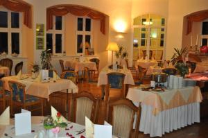 a restaurant with tables and chairs with white table cloth at Schlosshotel am Hainich in Behringen