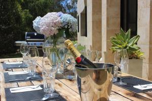 a table with a bottle of wine and a vase of flowers at The Summer House in Margaret River Town