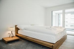 a white bedroom with a large bed and a window at Apartment JungfrauCenter Schynige Platte - GriwaRent AG in Interlaken