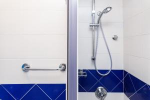 a shower in a bathroom with blue and white tiles at Bleu Village in Meta