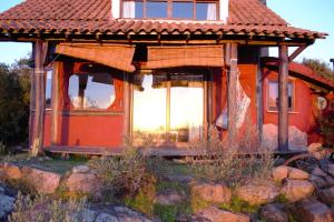 una pequeña casa con techo rojo en un campo en Tao Sierras De Aigua, en Aiguá