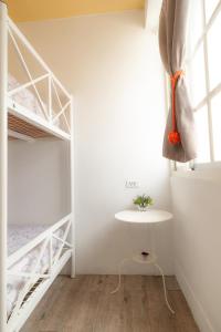 a small white room with a table and bunk beds at Hualien Bird's House Hostel in Hualien City