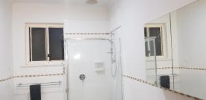 a white bathroom with a shower and a mirror at Unit in Marion in Sturt