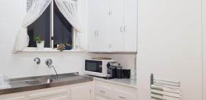 a kitchen with white cabinets and a sink and a microwave at Unit in Marion in Sturt