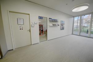 una stanza vuota con pareti bianche e porte in vetro di HITrental Allmend Comfort Studios a Lucerna