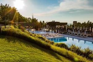 a swimming pool with lounge chairs and the sun shining at Palazzo di Varignana in Varignana