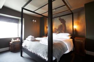 a bedroom with a canopy bed with a painting on the wall at The Kings Arms in Didmarton