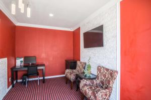 a room with a red wall with a chair and a desk at El Dorado Inn in Lynwood +16 photos