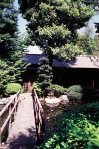 eine Brücke über einen Teich mit einem Baum und einem Gebäude in der Unterkunft Gyokutei in Hakone