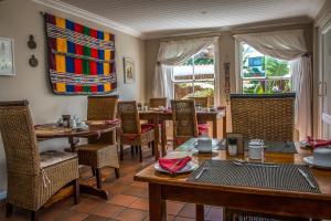 a dining room with tables and chairs and windows at African Breeze Guesthouse in Knysna