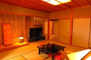 un salon avec une table et une télévision dans l'établissement OkutsuHotSpa IkedayaKajikaen, à Kagamino