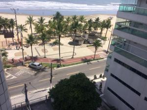 a view of a street with palm trees and a beach at Praia Grande Frente ao Mar-Albatroz in Praia Grande