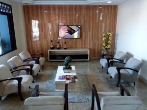 a waiting room with chairs and a flat screen tv at Hotel Praia e Mar in Aracaju