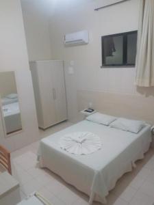 Hotel Praia e Mar في أراكاجو: غرفة نوم بسرير ابيض في غرفة