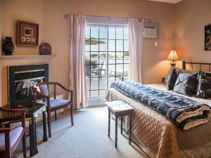 a bedroom with a bed and a chair and a fireplace at Inn on the Harbour and Telegraph House in Port Stanley