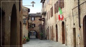 an alley in an old building with a flag at Hotel Ghibellino in Buonconvento