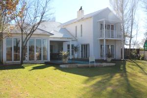Casa blanca con ventanas grandes y patio en Indigo Moon Guesthouse, en Lichtenburg
